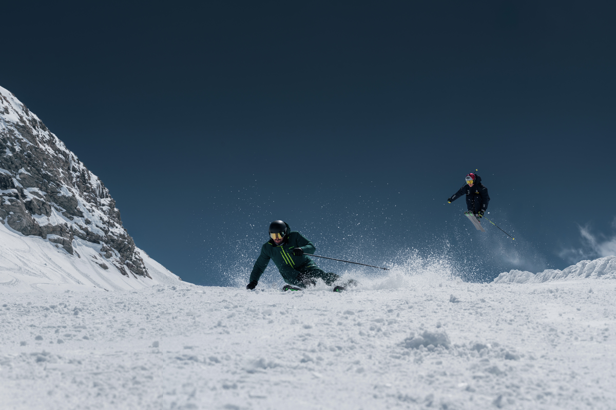 Two skiers in fresh snow beneath a blue sky
