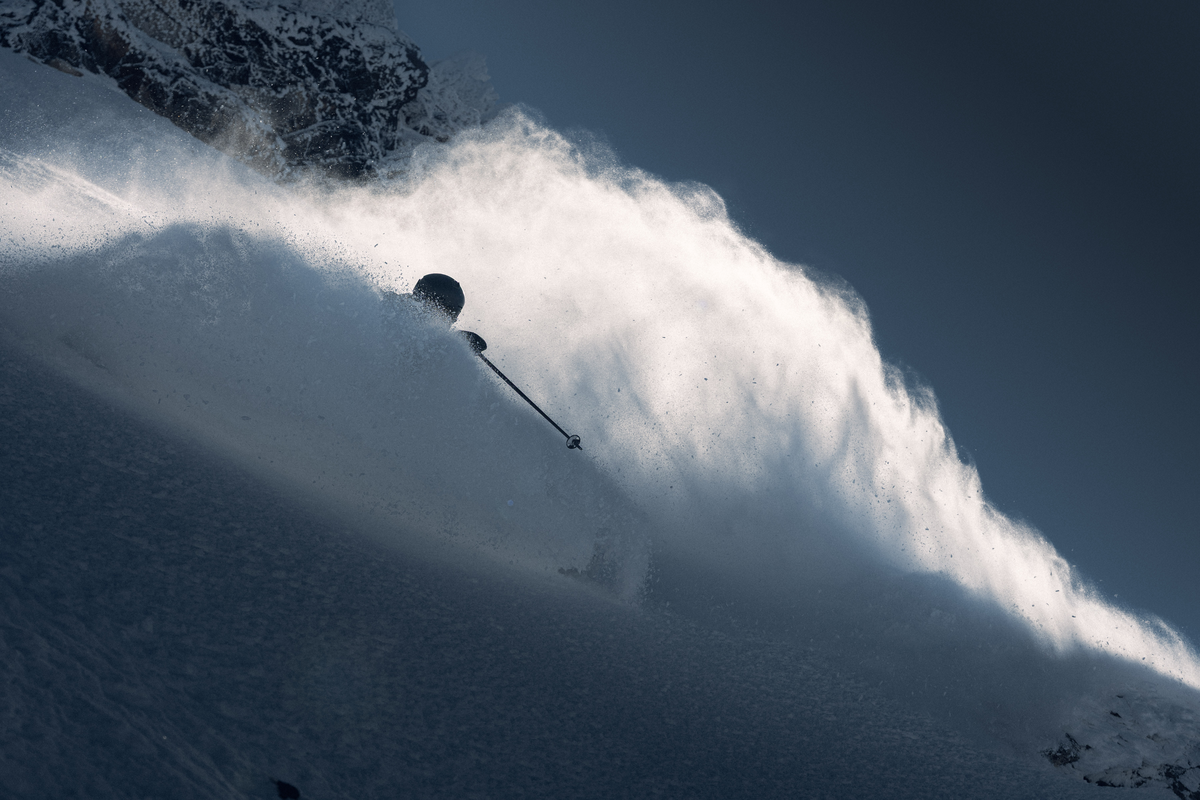 Skier surrounded by a cloud of backlit powder