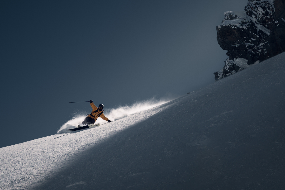 Skier in a yellow jacket on a sunlit snow slope