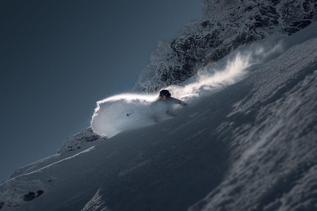 Skier carving a steep powder slope