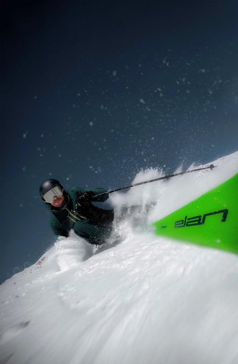 Skier in green with a bright green Elan ski in powder